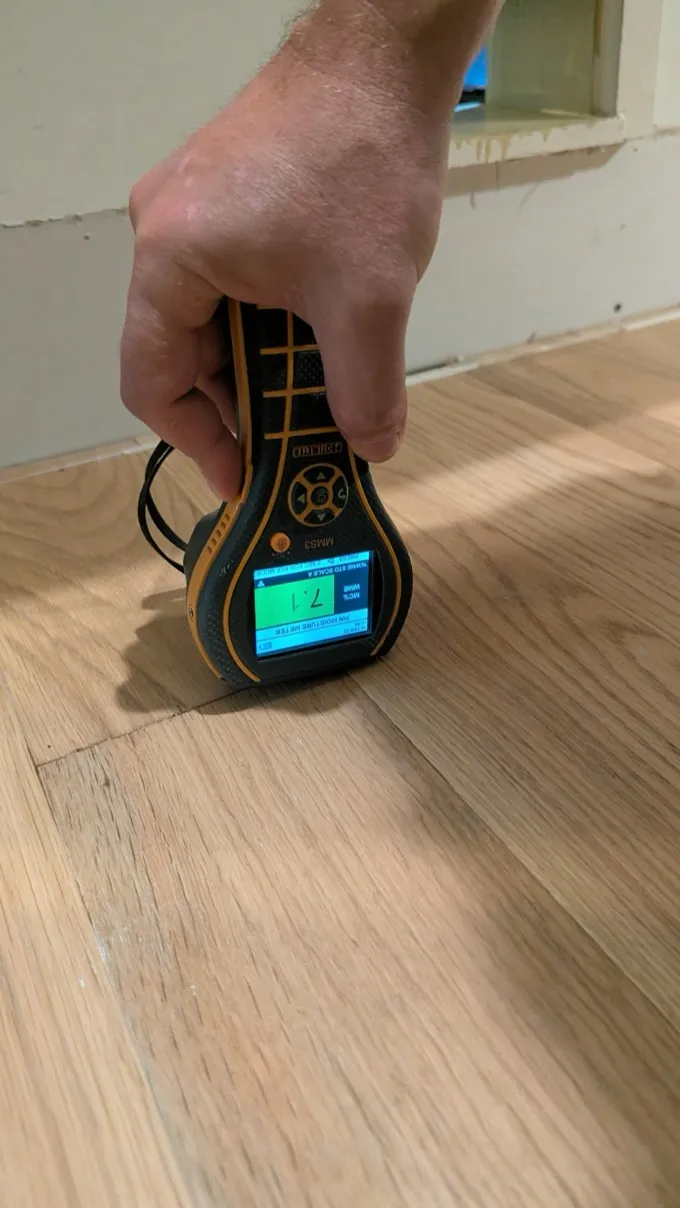 Moisture meter confirming dry readings after burst pipe repair in Austin